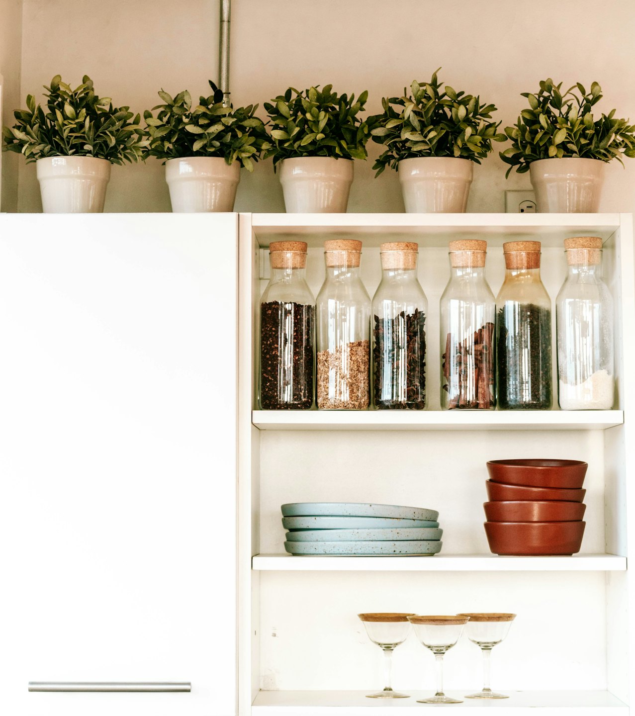 Kitchen shelves display organized jars of spices and stacked ceramic dishes.