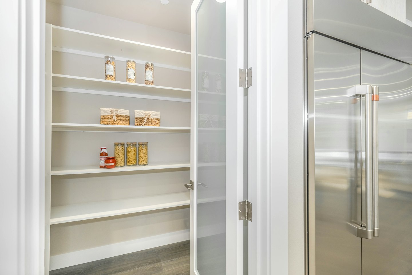 Modern kitchen pantry with white shelves and woven baskets.